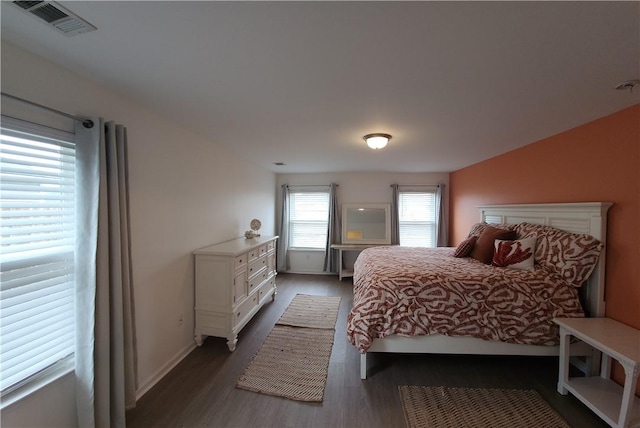 bedroom with wood finished floors, visible vents, and baseboards