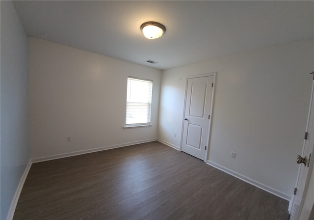 spare room with visible vents, baseboards, and dark wood-style floors