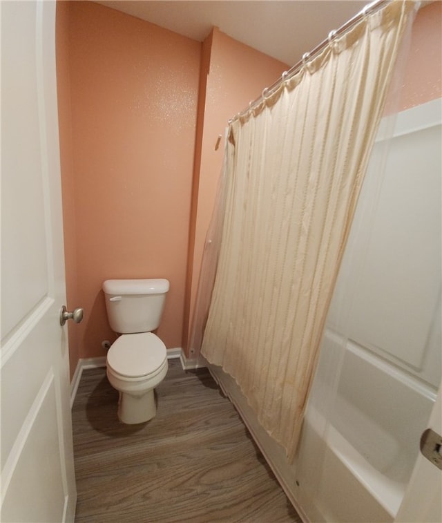 full bath with shower / bath combination with curtain, toilet, wood finished floors, and baseboards