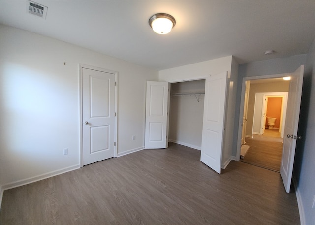 unfurnished bedroom featuring a closet, visible vents, baseboards, and wood finished floors