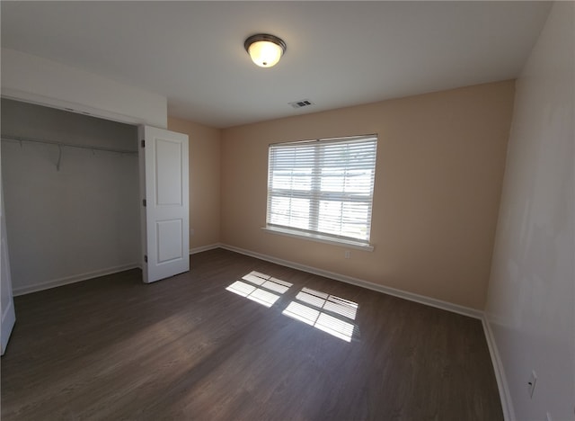 unfurnished bedroom with visible vents, baseboards, a closet, and dark wood-style floors