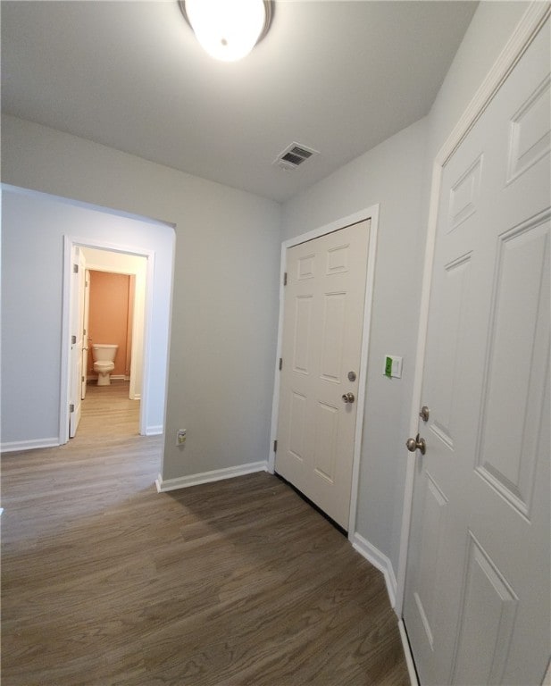 hallway with visible vents, baseboards, and wood finished floors