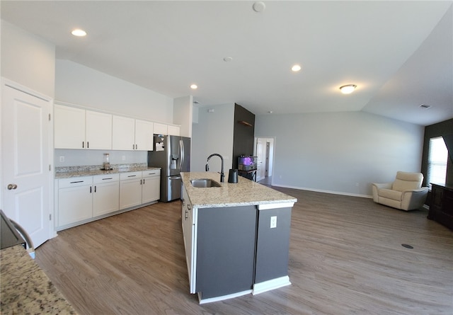 kitchen featuring light wood-type flooring, a sink, vaulted ceiling, stainless steel fridge, and open floor plan