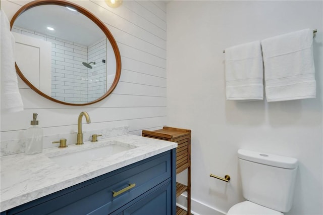 bathroom with vanity, wooden walls, and toilet