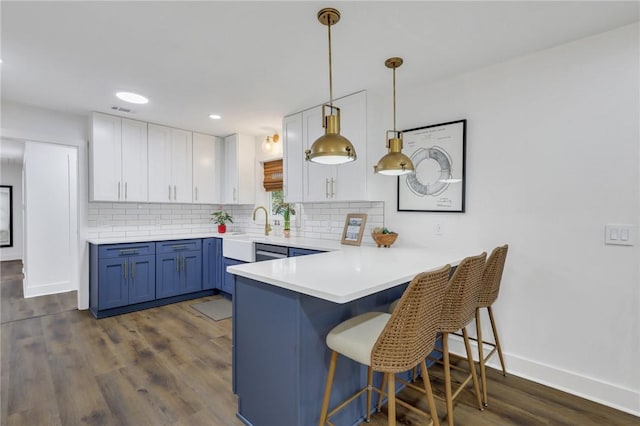 kitchen featuring dark wood-type flooring, blue cabinets, hanging light fixtures, decorative backsplash, and white cabinets