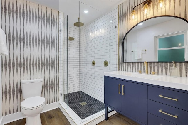 bathroom featuring hardwood / wood-style flooring, toilet, vanity, and a shower with shower door