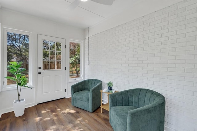 sitting room with ceiling fan, brick wall, and dark hardwood / wood-style flooring