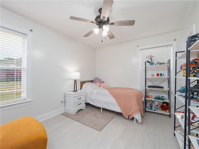 bedroom with a ceiling fan, baseboards, and wood finished floors