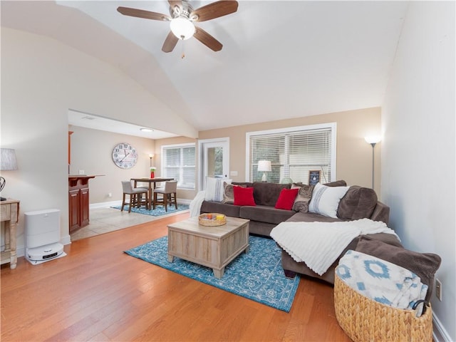 living room with light wood-type flooring, baseboards, and vaulted ceiling