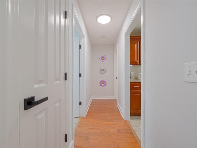 corridor with baseboards and light wood-style floors