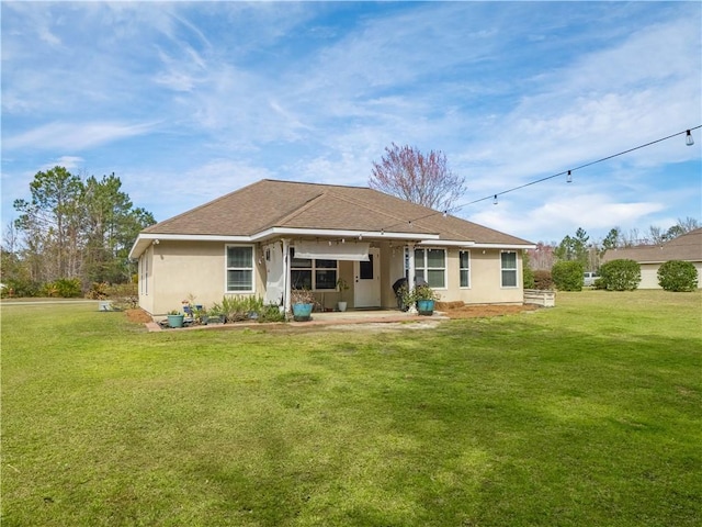 back of house with roof with shingles, a lawn, and stucco siding