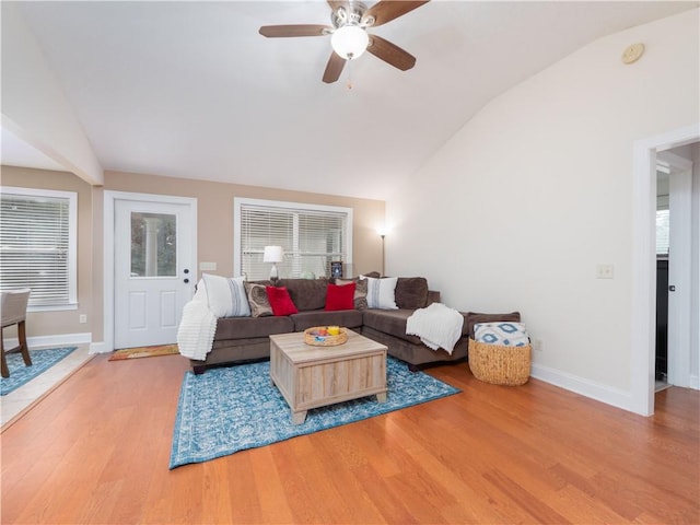 living area with a healthy amount of sunlight, baseboards, vaulted ceiling, and wood finished floors