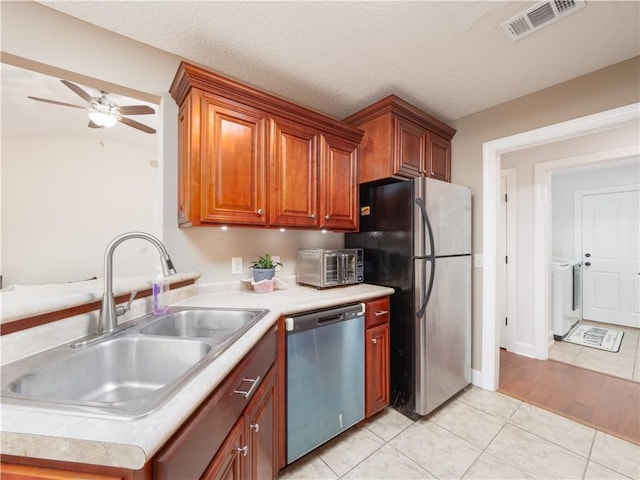 kitchen with light tile patterned floors, visible vents, appliances with stainless steel finishes, light countertops, and a sink