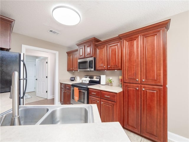 kitchen featuring light countertops, visible vents, appliances with stainless steel finishes, a sink, and a textured ceiling