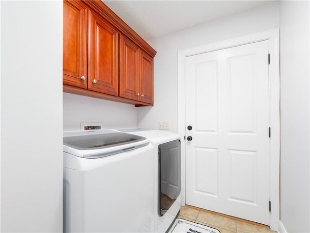 clothes washing area with light tile patterned floors, cabinet space, and separate washer and dryer