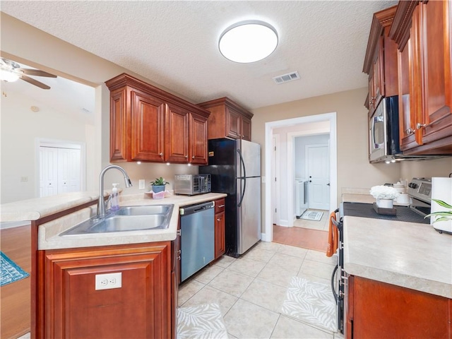 kitchen with light tile patterned floors, stainless steel appliances, light countertops, visible vents, and a sink