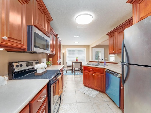 kitchen with light tile patterned floors, stainless steel appliances, a sink, visible vents, and light countertops