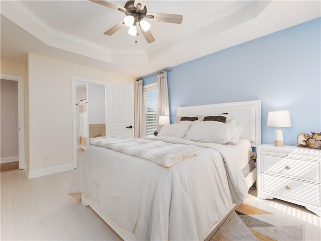 bedroom with baseboards, a raised ceiling, a ceiling fan, crown molding, and light wood-style floors