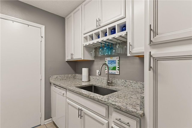 kitchen with a sink, white dishwasher, and white cabinetry