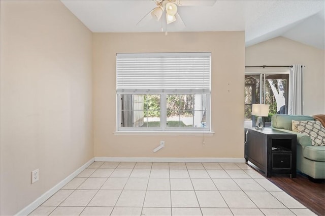 empty room featuring ceiling fan, plenty of natural light, light tile patterned floors, and vaulted ceiling