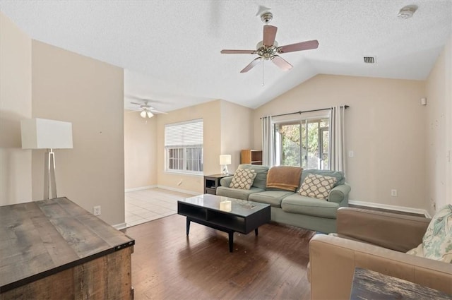 living room with wood-type flooring, a textured ceiling, ceiling fan, and lofted ceiling