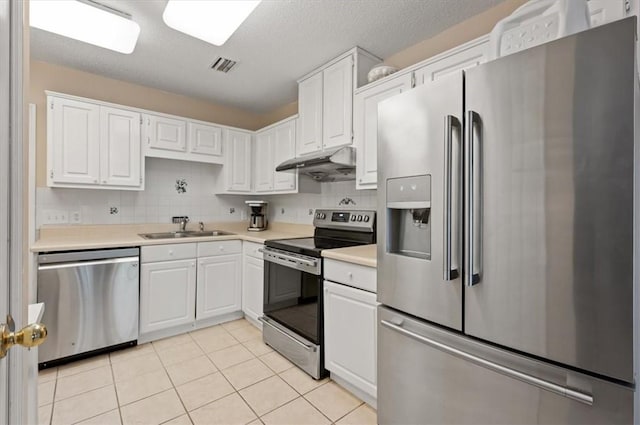 kitchen featuring decorative backsplash, stainless steel appliances, sink, white cabinetry, and light tile patterned flooring