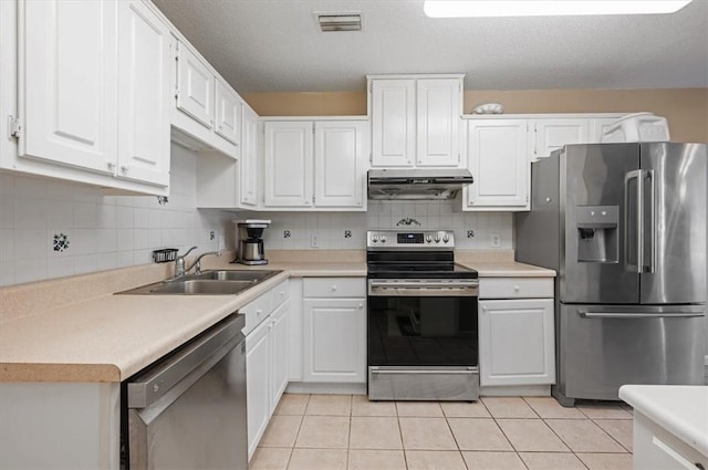 kitchen featuring sink, light tile patterned flooring, decorative backsplash, white cabinets, and appliances with stainless steel finishes