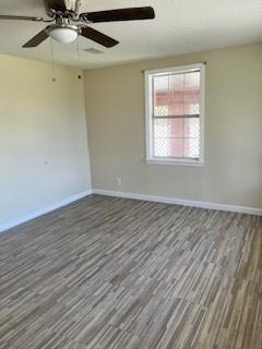 unfurnished room with ceiling fan, baseboards, and wood finished floors