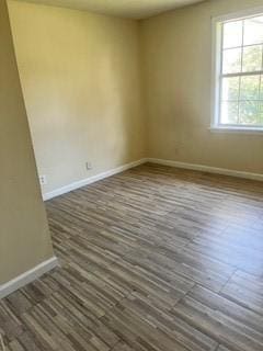 empty room featuring baseboards and dark wood-style flooring