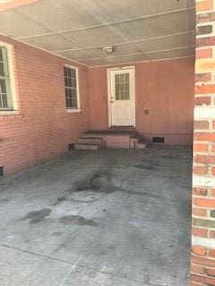 doorway to property with an attached carport and brick siding