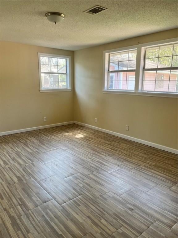 unfurnished room featuring visible vents, baseboards, and wood finished floors