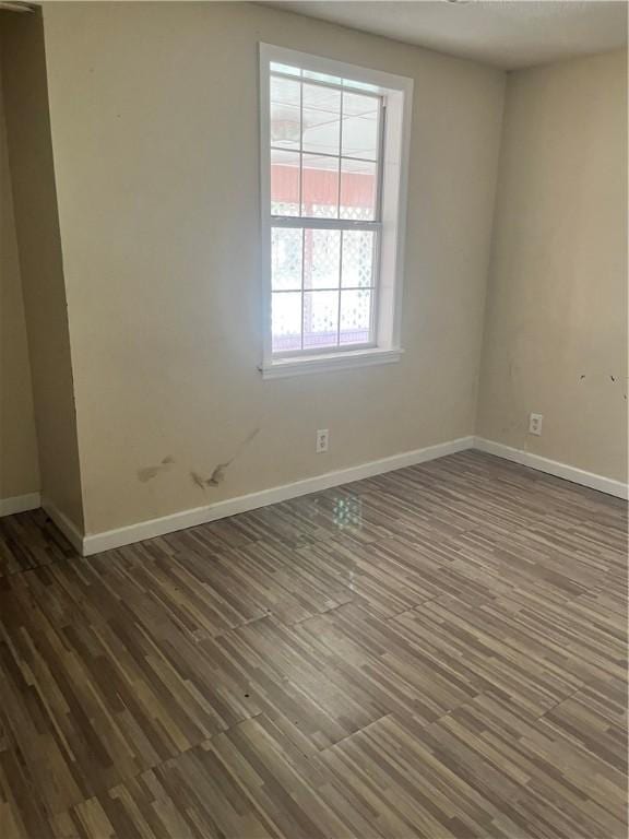 unfurnished room with baseboards and dark wood-type flooring