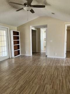 unfurnished living room featuring dark wood-style flooring, a textured ceiling, ceiling fan, and vaulted ceiling