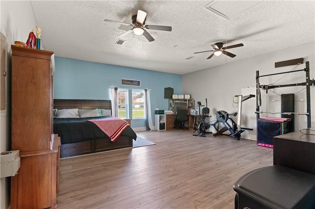 bedroom with visible vents, a textured ceiling, ceiling fan, and wood finished floors