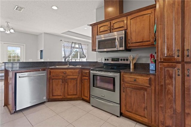 kitchen with visible vents, a sink, appliances with stainless steel finishes, a peninsula, and a healthy amount of sunlight