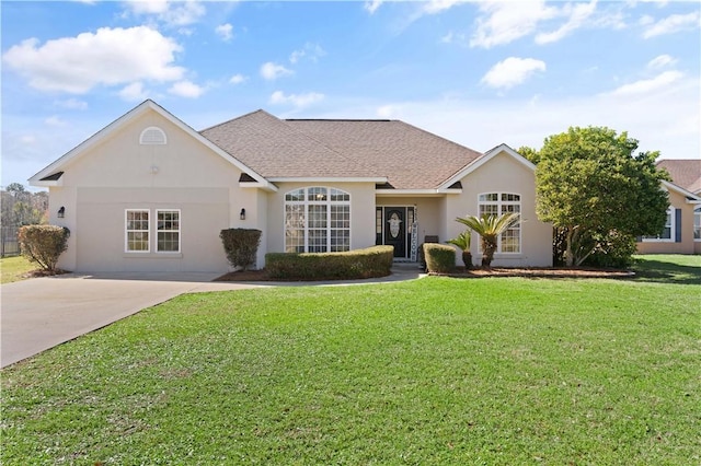 ranch-style house with a front lawn, driveway, roof with shingles, and stucco siding