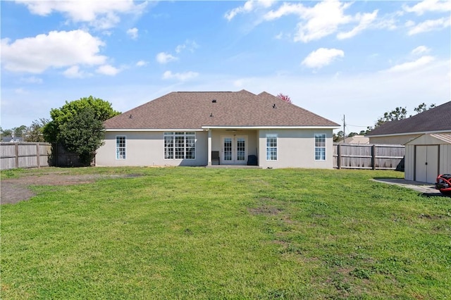 rear view of house featuring a shed, stucco siding, french doors, and a fenced backyard