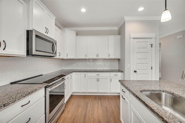 kitchen with stainless steel appliances, white cabinets, and decorative light fixtures