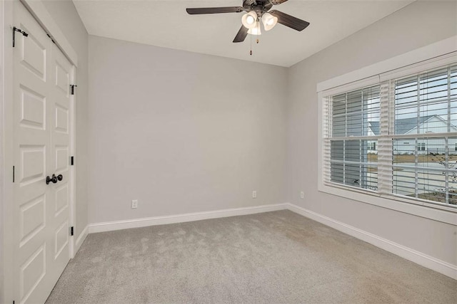 spare room featuring ceiling fan, light carpet, and a wealth of natural light