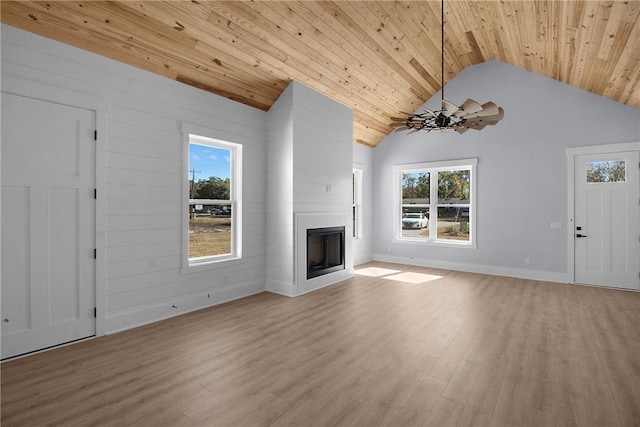 unfurnished living room with vaulted ceiling, wooden ceiling, wood finished floors, a large fireplace, and an inviting chandelier