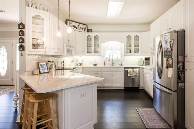 kitchen with dark hardwood / wood-style floors, kitchen peninsula, hanging light fixtures, appliances with stainless steel finishes, and white cabinets