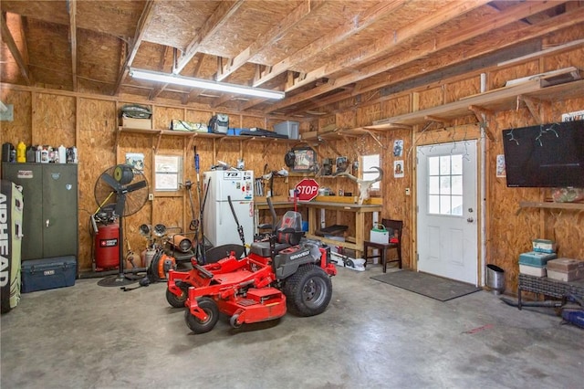 garage featuring white refrigerator and wooden walls