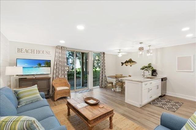 living room with sink, light hardwood / wood-style flooring, a wall of windows, and ceiling fan