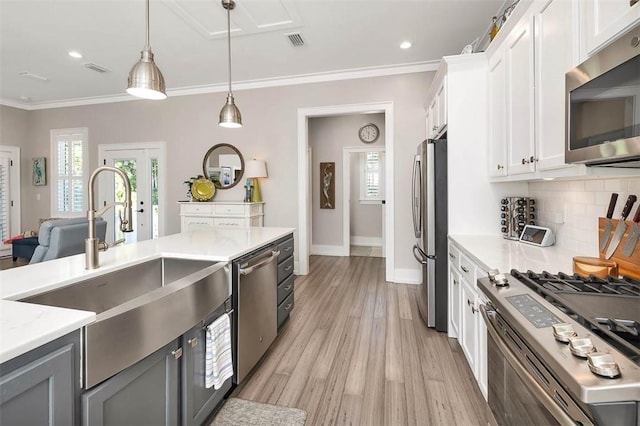 kitchen featuring sink, white cabinetry, crown molding, pendant lighting, and stainless steel appliances