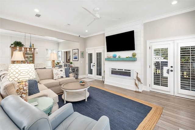 living room featuring hardwood / wood-style flooring, ornamental molding, ceiling fan, and french doors