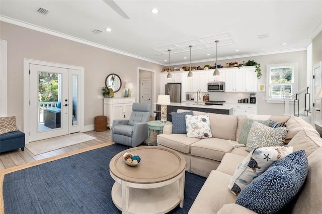 living room with sink, crown molding, and light hardwood / wood-style flooring