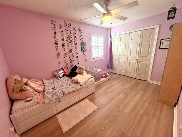 bedroom with a textured ceiling, ceiling fan, baseboards, light wood-style floors, and a closet