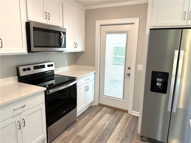 kitchen with white cabinetry, ornamental molding, stainless steel appliances, and light hardwood / wood-style floors