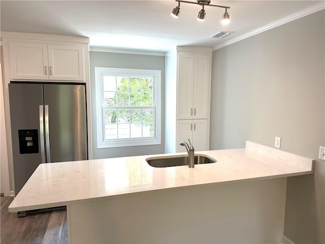 kitchen with sink, light stone counters, dark hardwood / wood-style floors, stainless steel fridge, and white cabinets