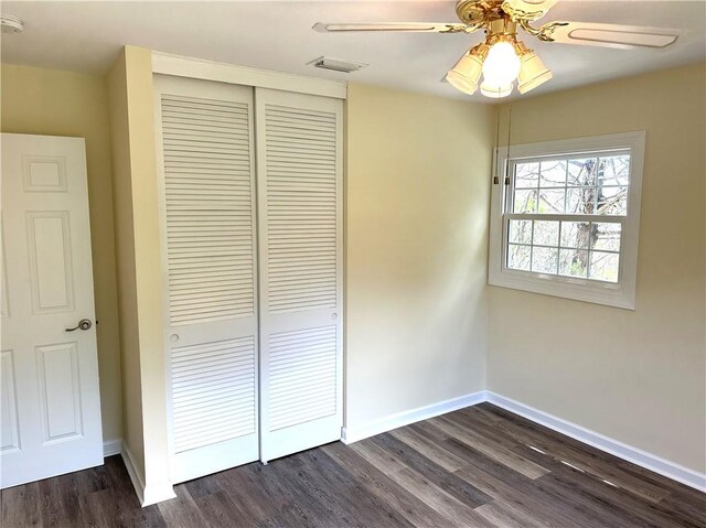 unfurnished bedroom with ceiling fan, a closet, and dark hardwood / wood-style floors